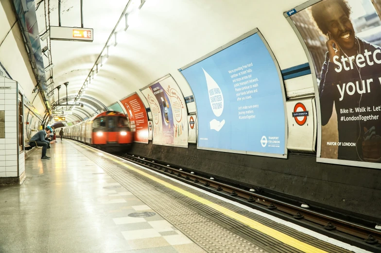 a metro train traveling through a train station next to poster ads