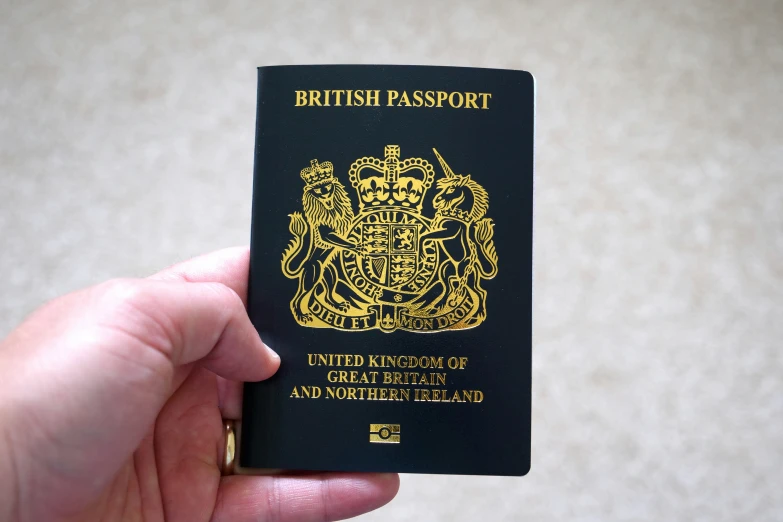 a british passport in hand that is being held up