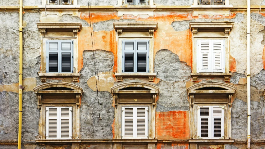 old yellow brick building with six windows and shutters