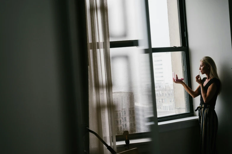 a woman standing next to a window with sunlight coming through