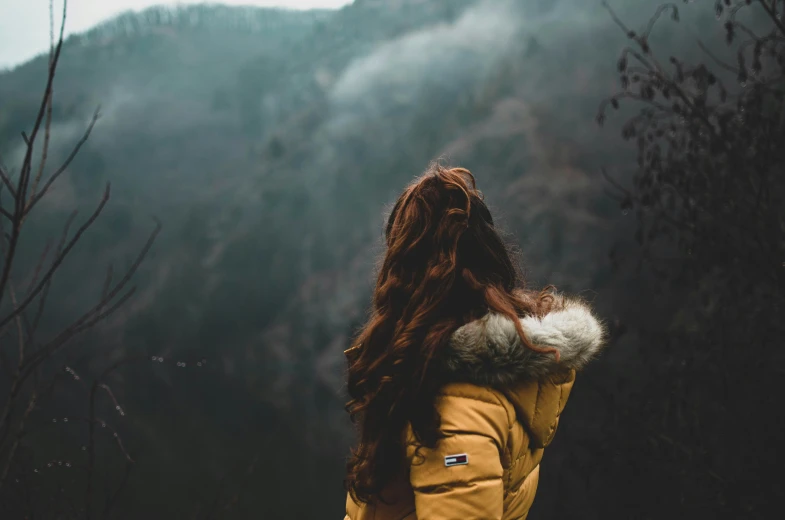 a woman wearing a yellow winter coat in the mountains