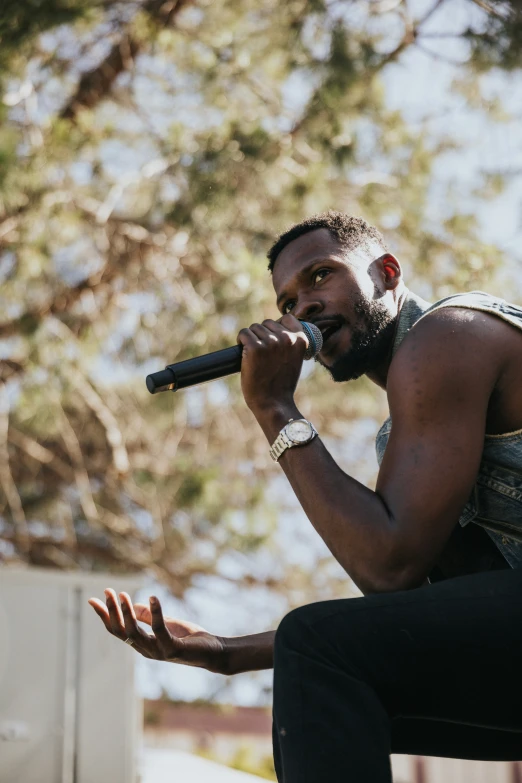 a man with beard sitting down holding onto a microphone