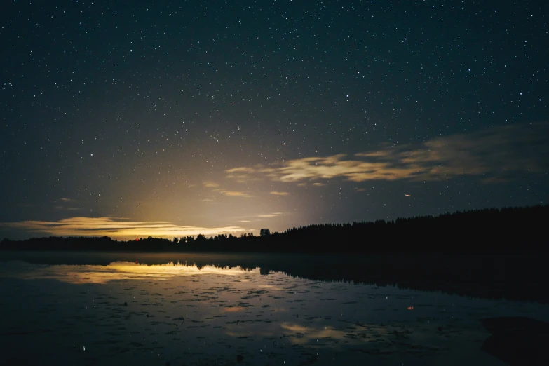 a lake at night with the stars reflected in the water