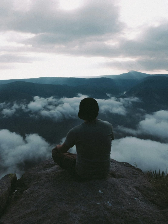 a person sitting on a rock looking over a valley