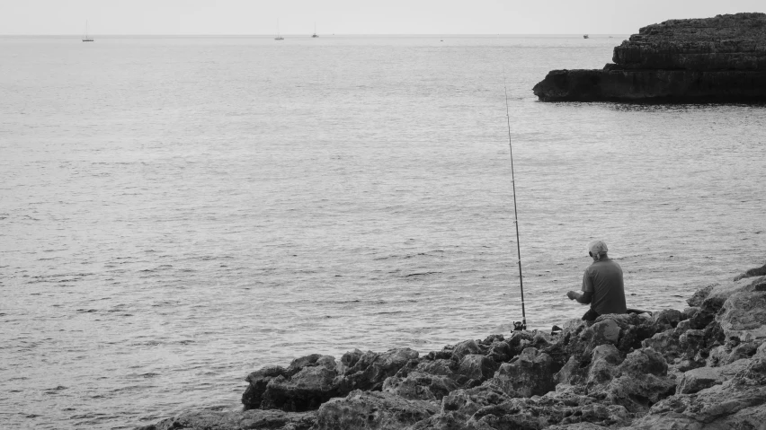 a black and white po of a person on the shore fishing