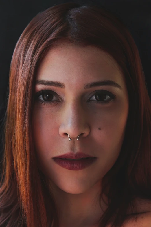 a beautiful young woman with red hair wearing a nose ring