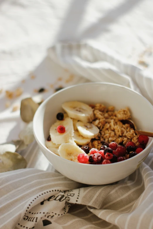 a bowl filled with granola and fruit on top of a white table cloth