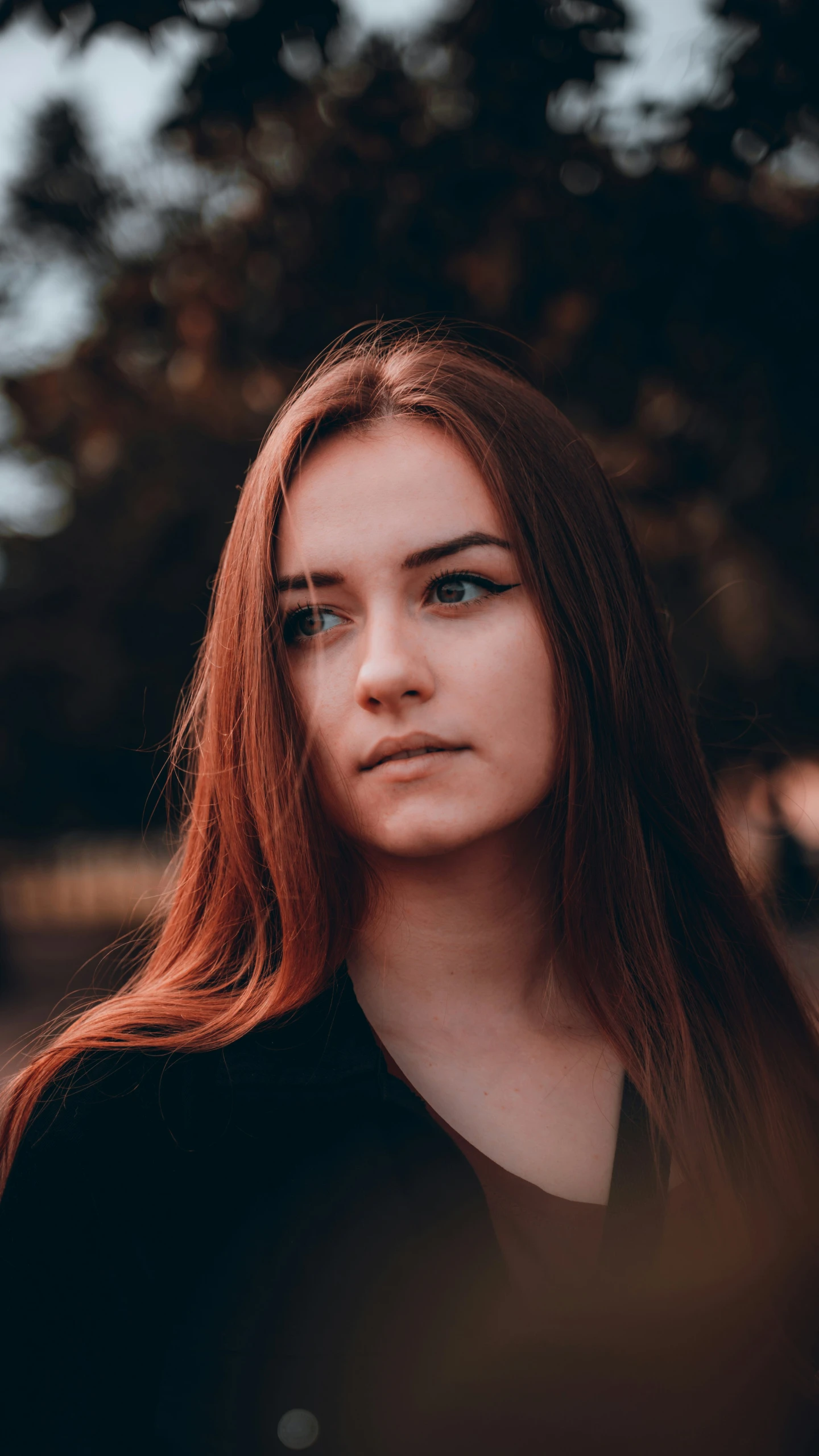 young woman with red hair looking away while standing