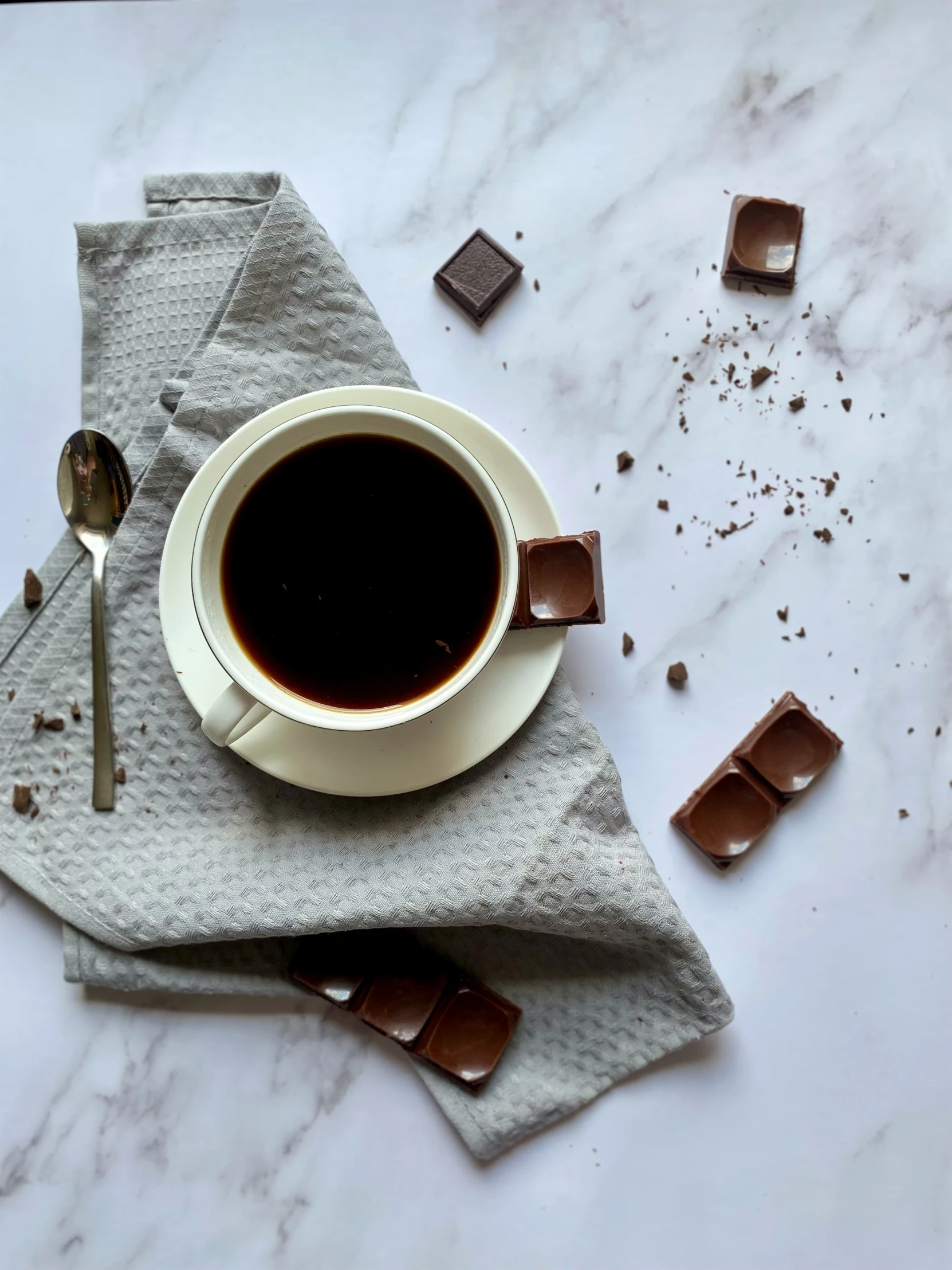 a white cup of coffee with some chocolate on the table