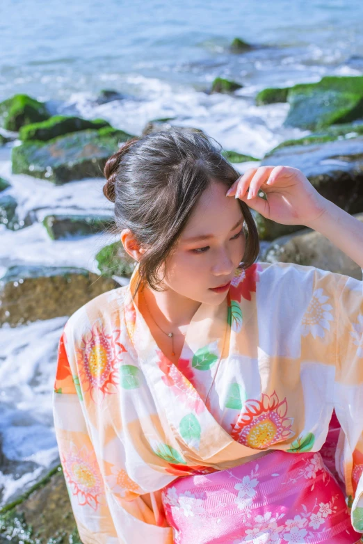 a woman sitting next to some water wearing a kimono