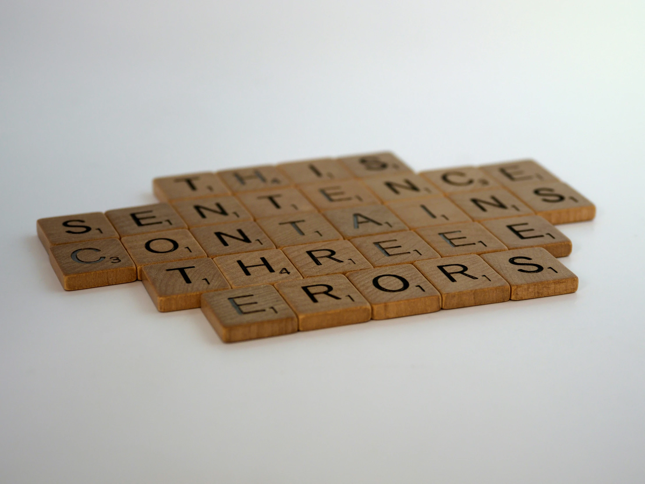 three scrabble tiles of the words toinn and contaments for errors