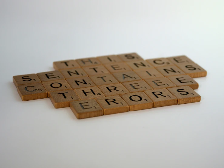 three scrabble tiles of the words toinn and contaments for errors
