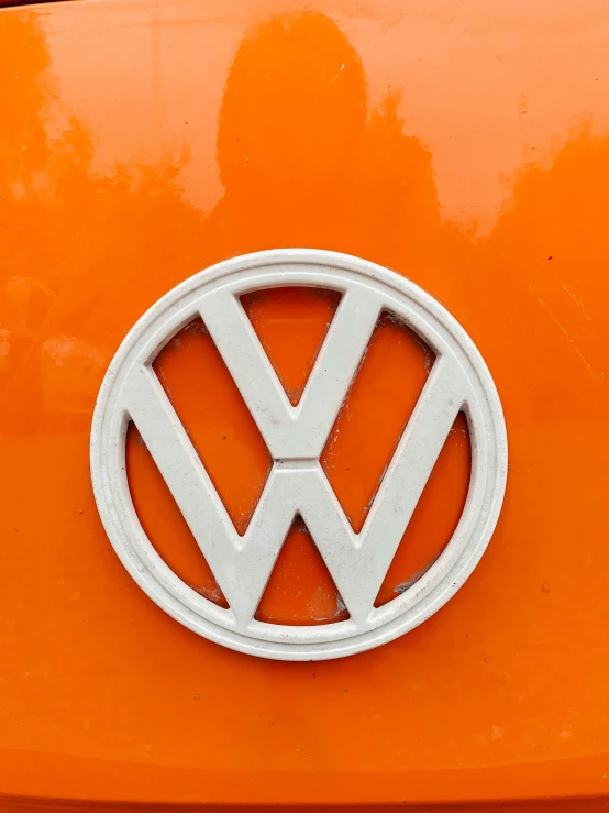 the front of a volkswagen logo on an orange colored vehicle