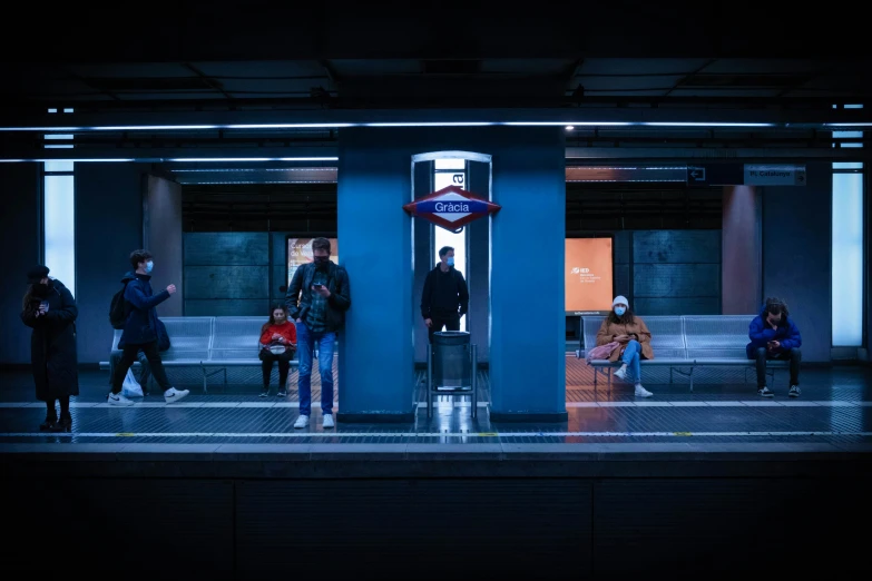 people stand at a subway station with blue walls