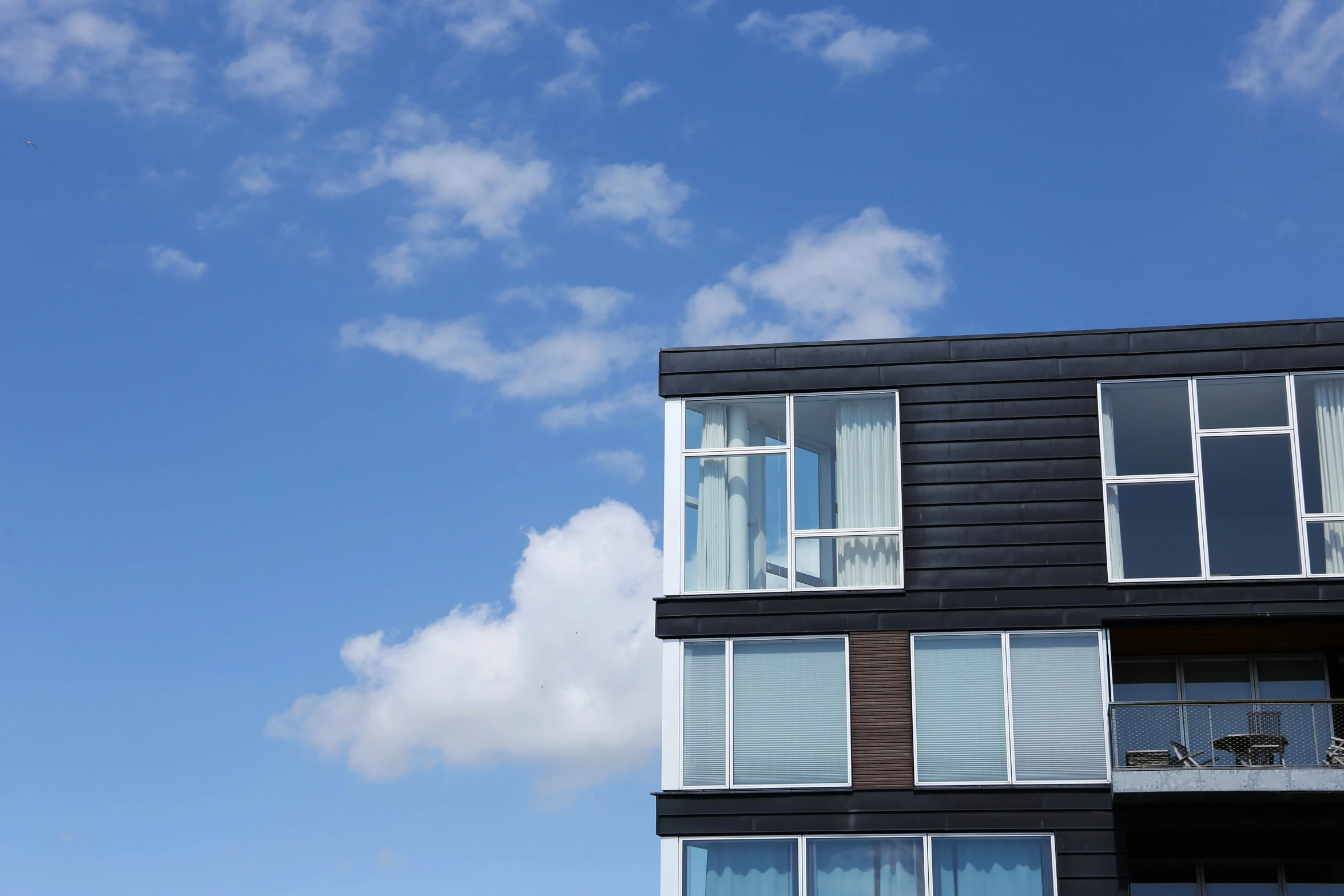 a building with several windows has a blue sky with white clouds