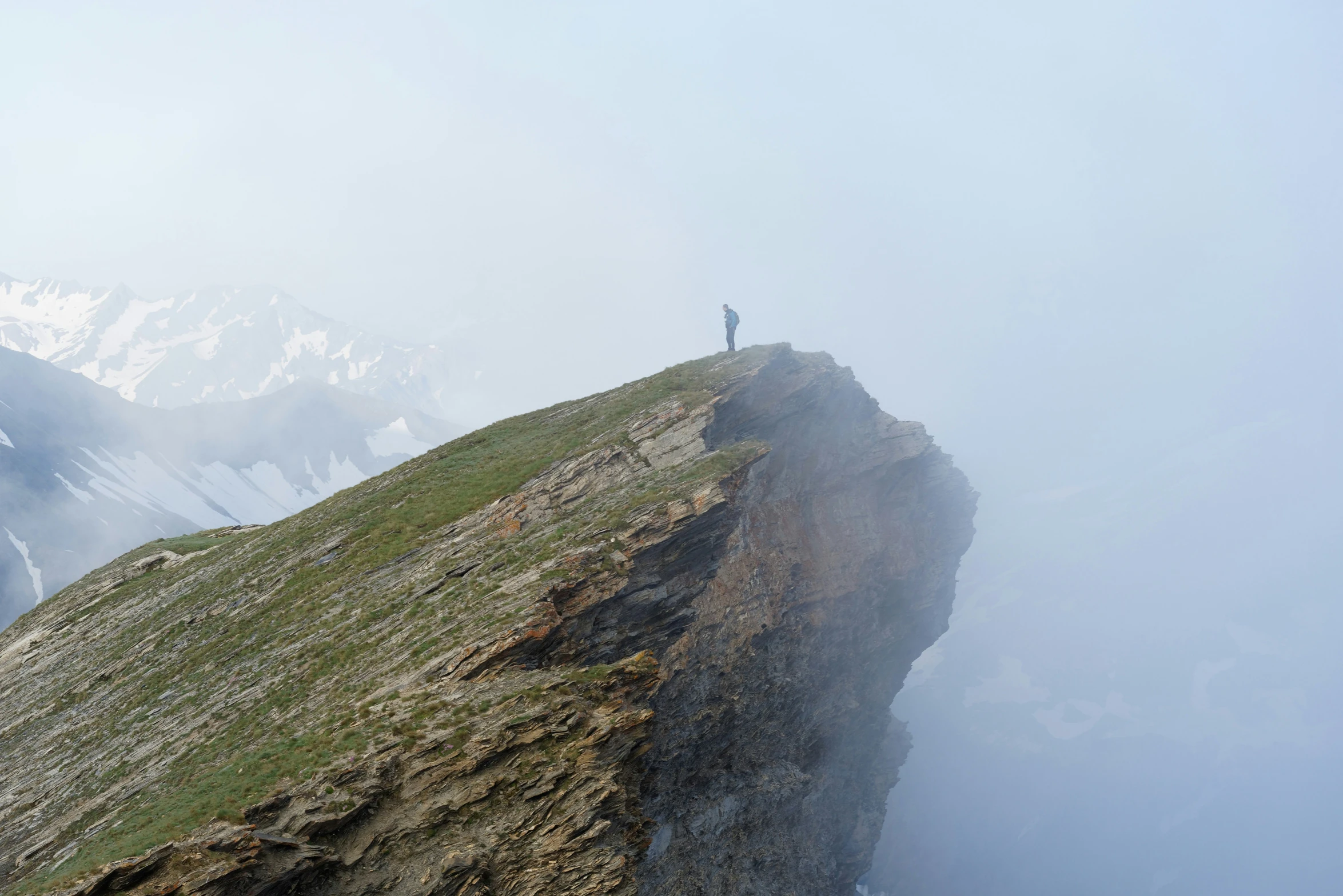 a man stands on a cliff above the clouds