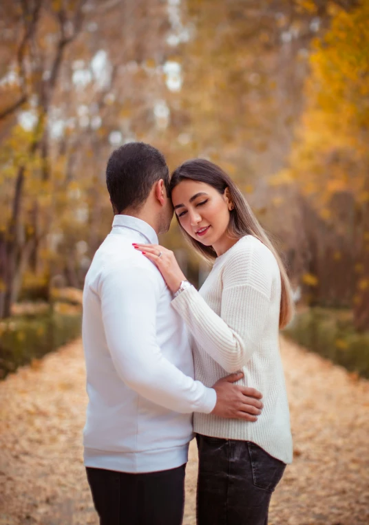 the engaged couple emce as they stand on a path surrounded by autumn trees