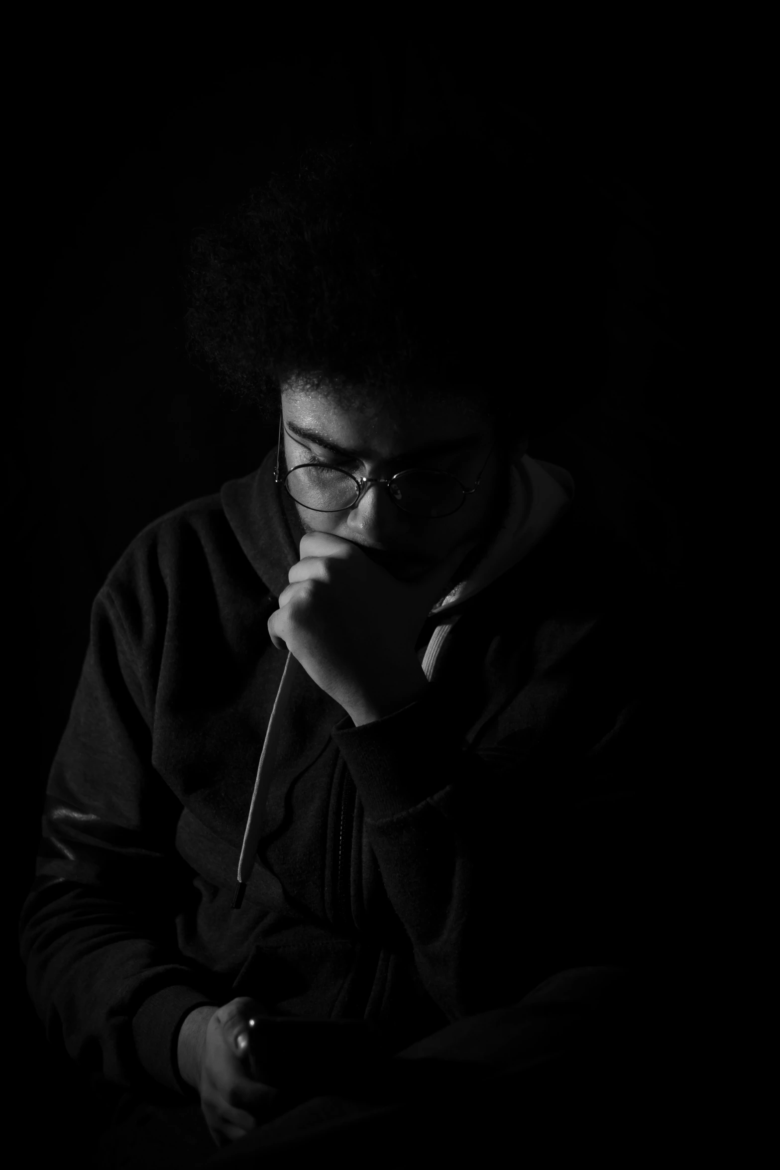 a woman with an afro and glasses in a dark background