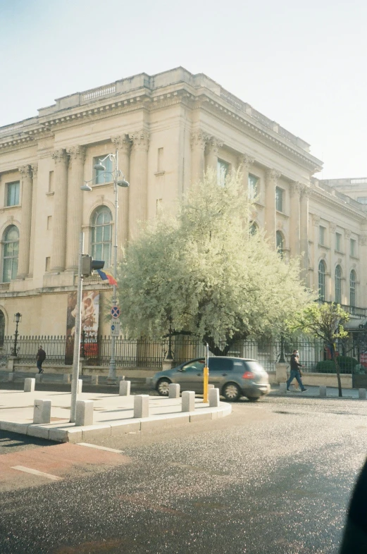 there is a very large building that has a tree and people in front of it