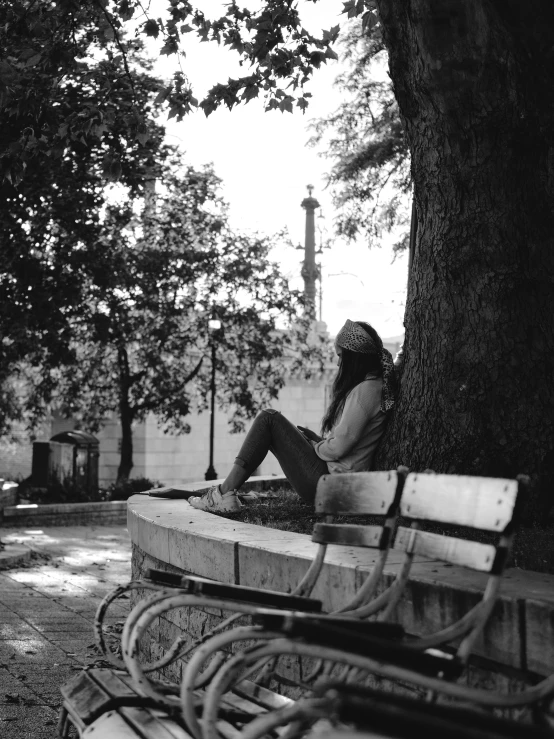 a woman sitting on a bench next to trees