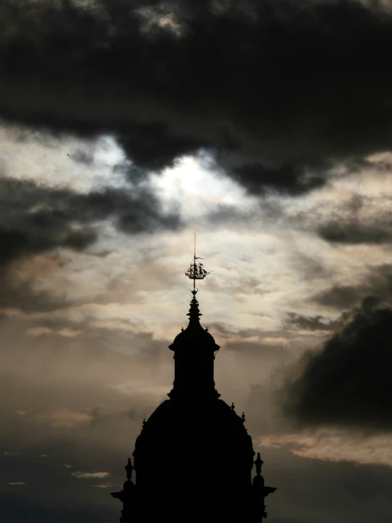 a sky view of a church spire with a dark cloud