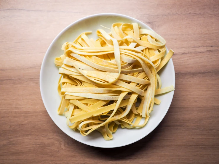 a white plate filled with pasta on top of a wooden table