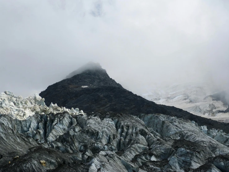 snow covered mountain and rock formations in the foreground