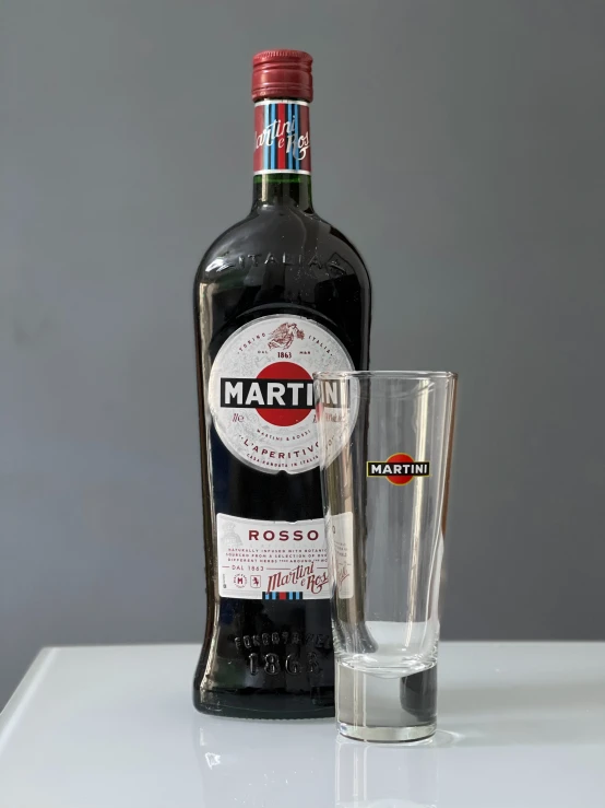 a bottle of martini sits next to an empty s glass