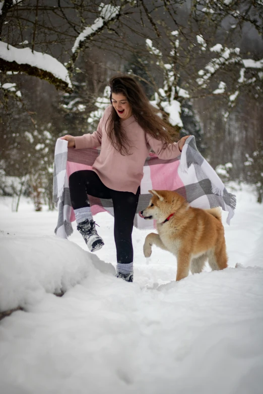 a woman with two dogs playing in the snow