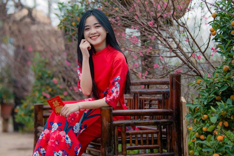 a woman in a red and blue dress smiles while sitting on a bench