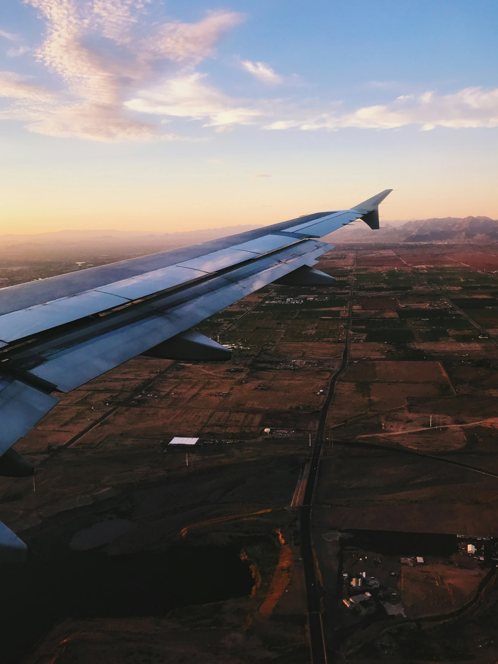 a wing over a desert plain with a sky background