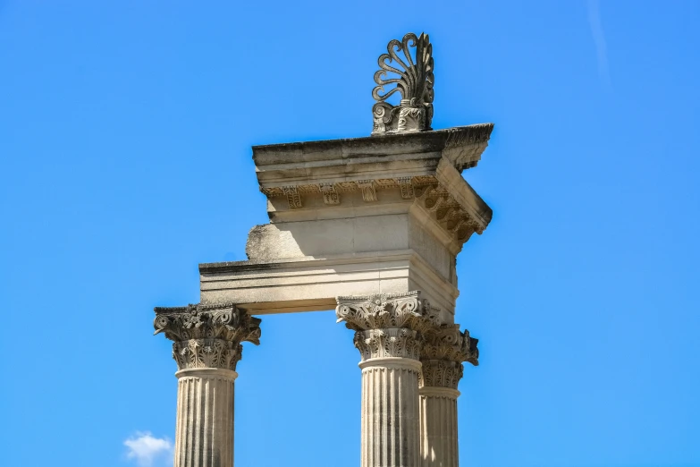 the top part of an ornate, well - kept column stands against a blue sky