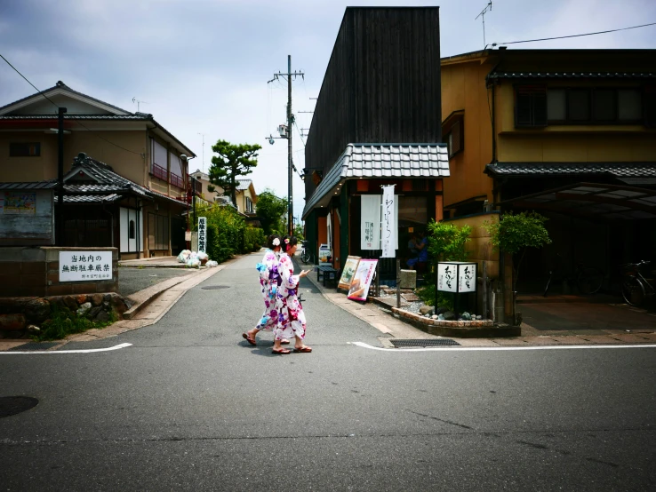 two woman crossing the street on a street with buildings