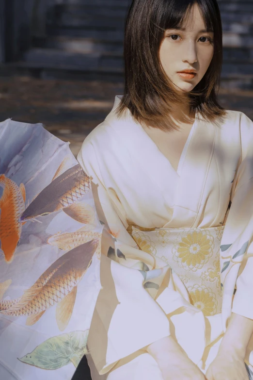 a woman sitting on the ground in a dress with a fan in her hand