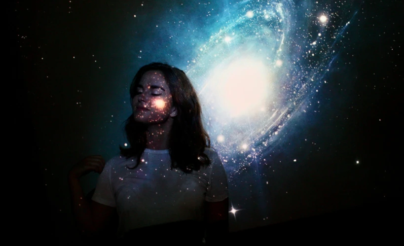 a person wearing white standing in front of a space background