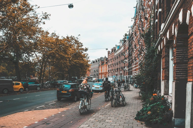 several people walking and riding bicycles down a brick street