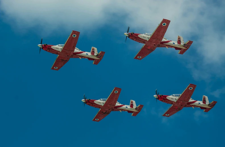 three stunt airplanes flying in formation overhead in the blue sky