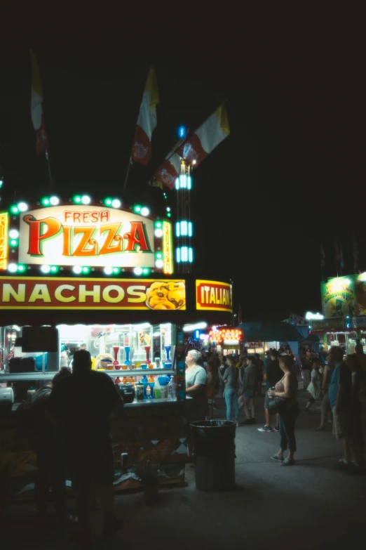 people standing and sitting around at a food stand