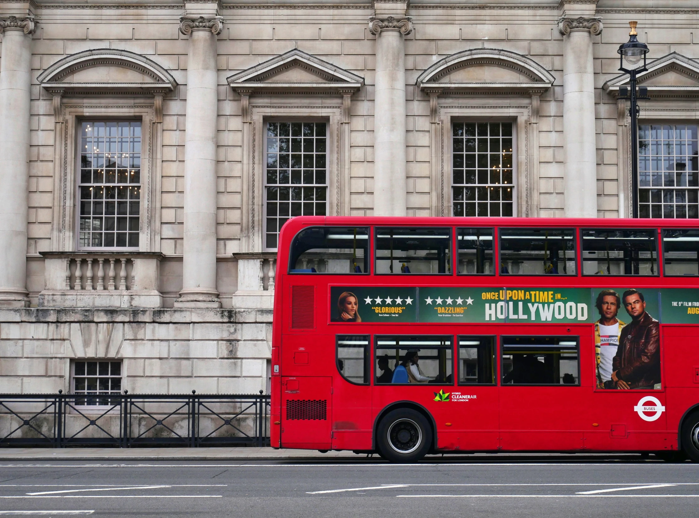a large red double decker bus parked outside of a very old building