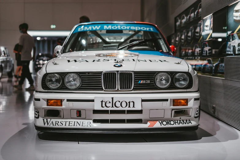 a white bmw parked in a showroom next to people