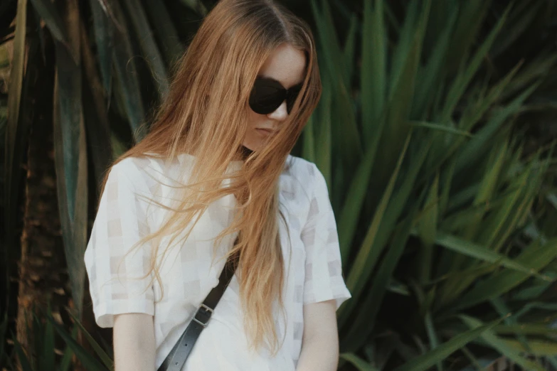 a girl with long red hair and black sunglasses is wearing a white shirt