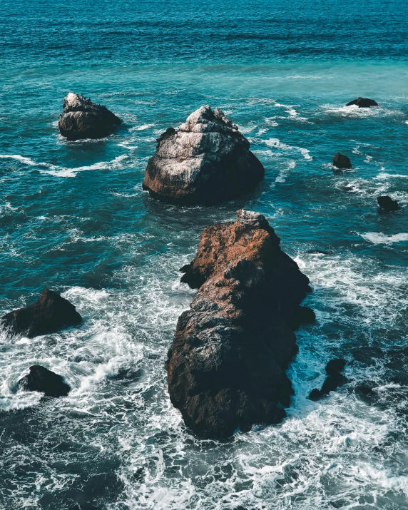 three large rocks that are in the middle of some water