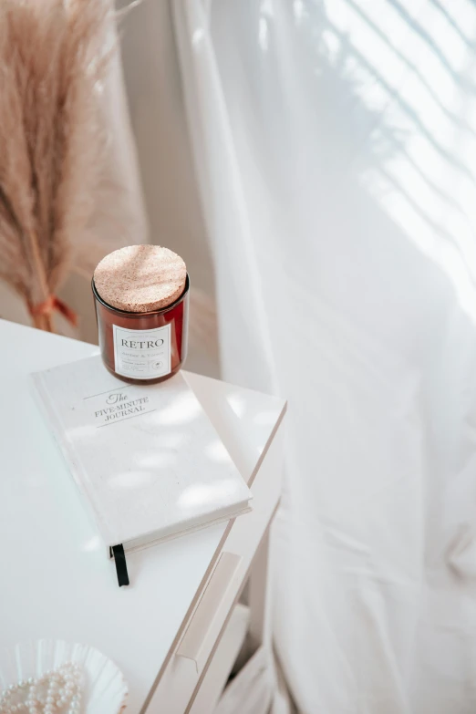 an open book on a small table next to a jar of lip polish