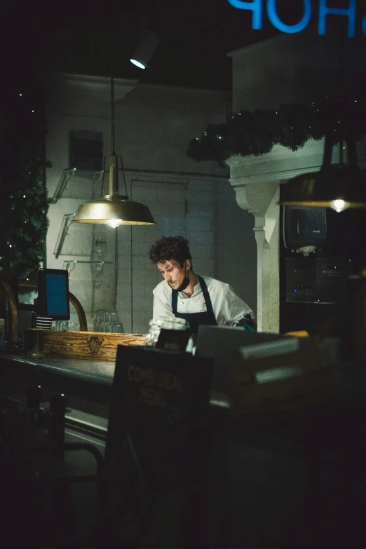 a young man standing at the counter of a restaurant in front of a store sign