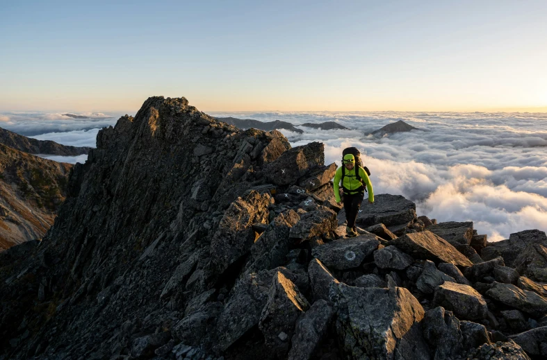 the man standing on top of a tall rock covered in clouds