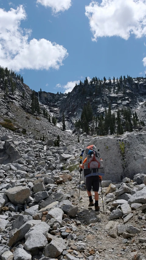 a person wearing backpacks hiking up rocks