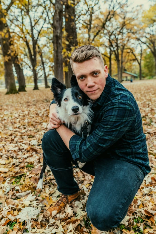 man with dog posing for a po on leaves in the park