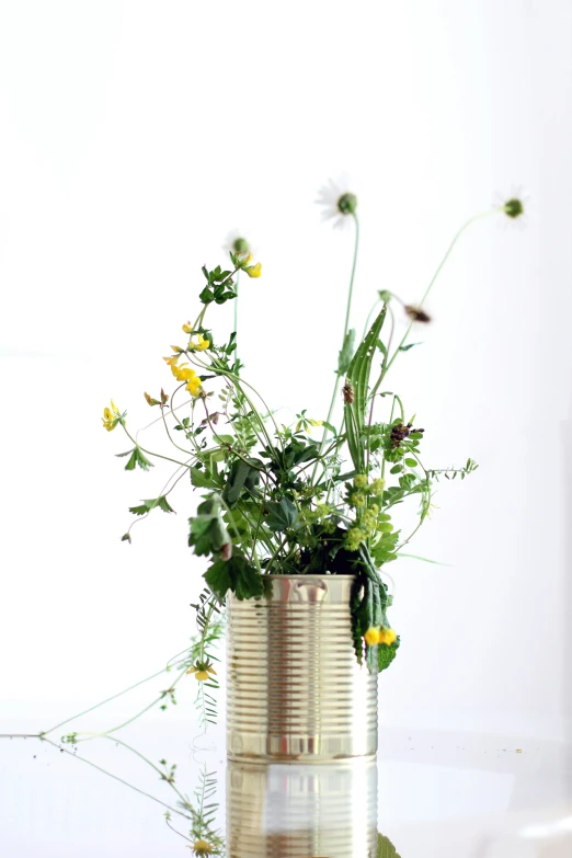 an antique tin can with yellow flowers on top