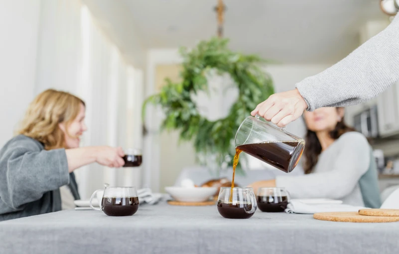 a woman pouring syrup into coffee cups at the table