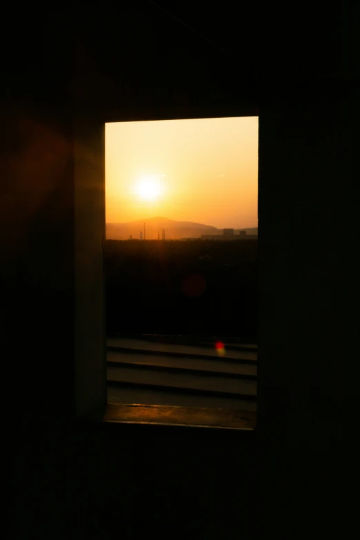 the view out of a door of a sunrise and hills